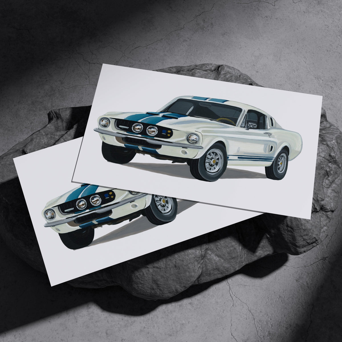 Two white Ford Mustang GT500 art prints resting on a dark stone surface