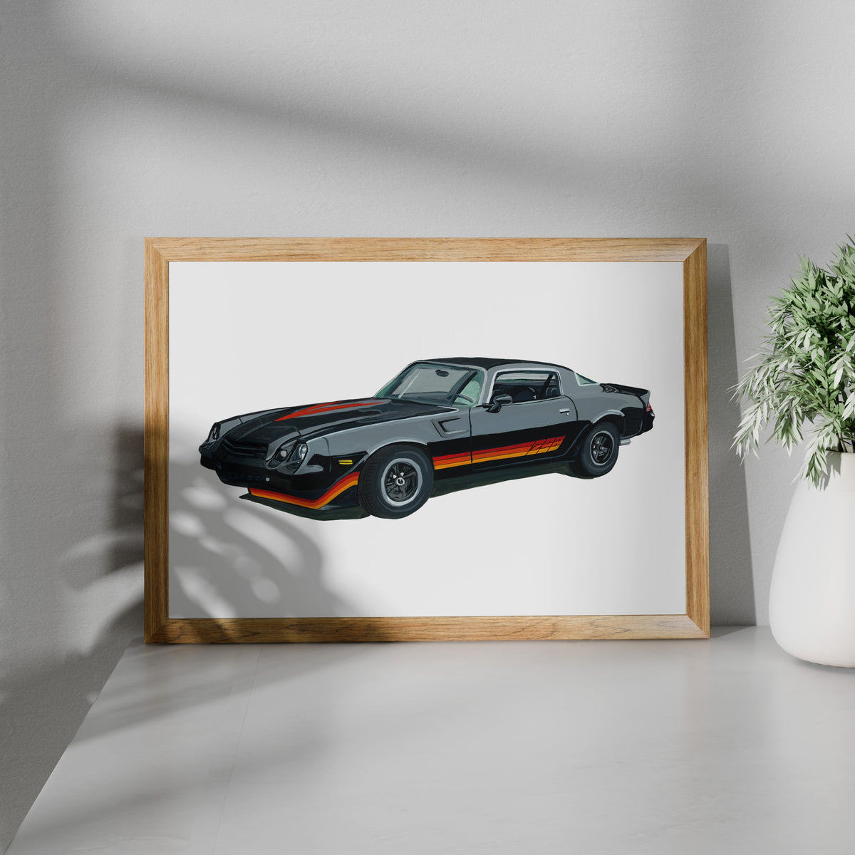 Framed black Chevrolet Camaro Z28 art print shown at an angle on a white surface