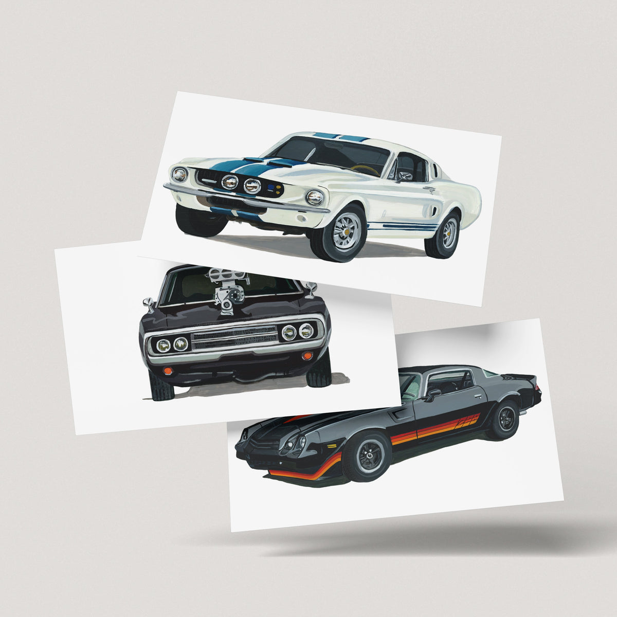 Ford Mustang GT500, Chevrolet Camaro Z28 and Dodge Charger R/T art prints fanned out on an off-white background