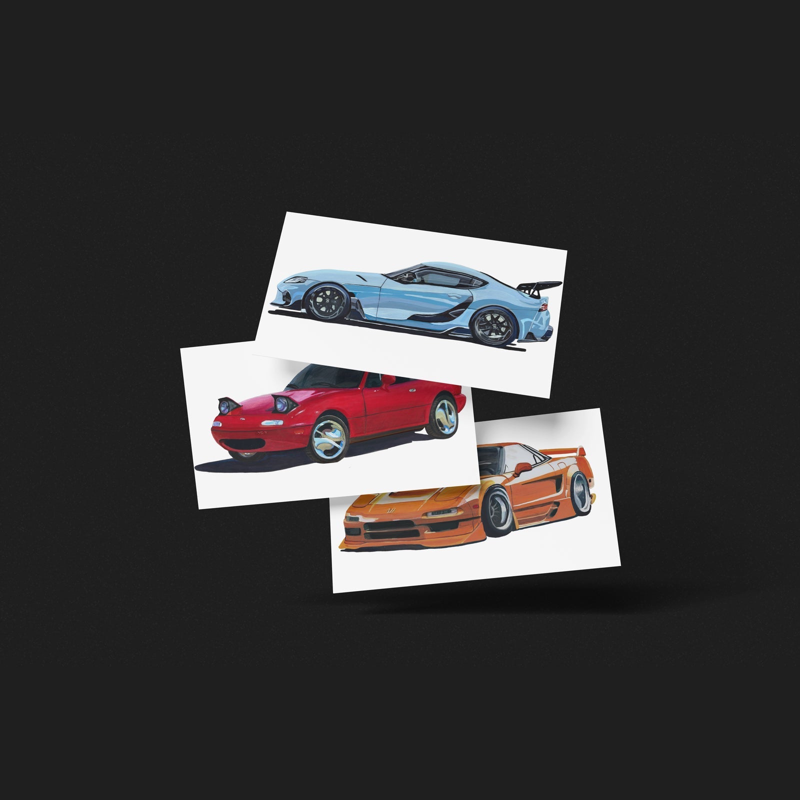 Three car art prints in light blue, red and orange fanned out on a black background