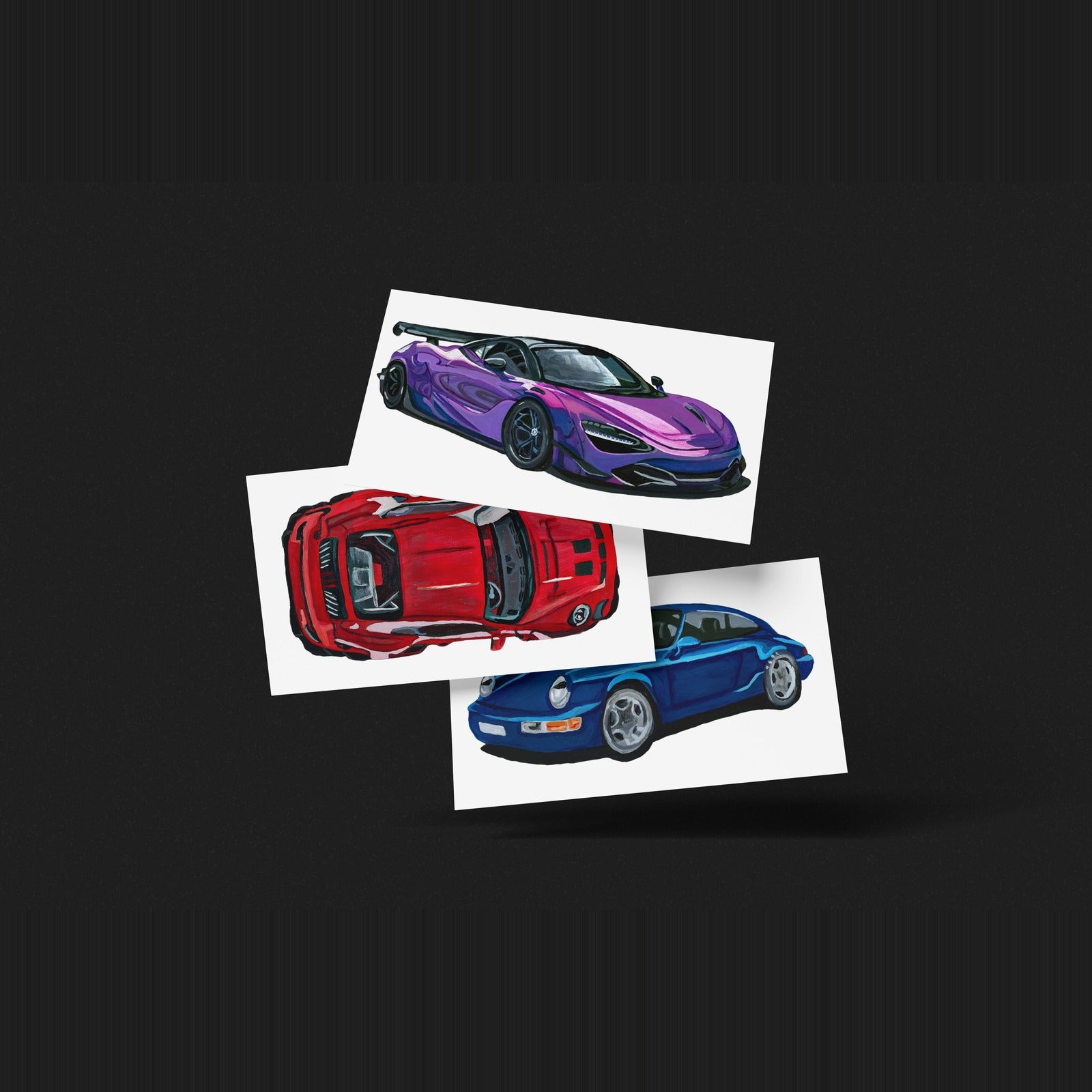 Three car art prints fanned out on a dark background