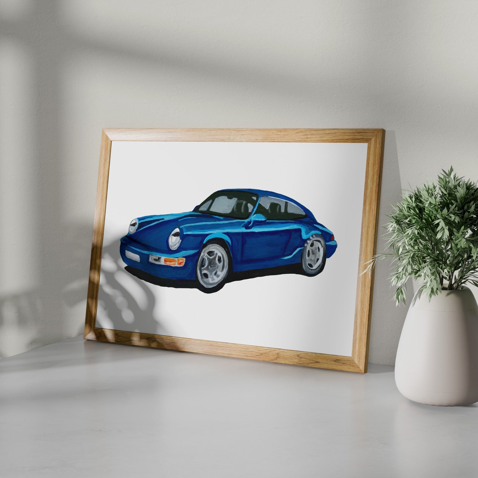 Framed blue classic sports car art print styled on a white shelf